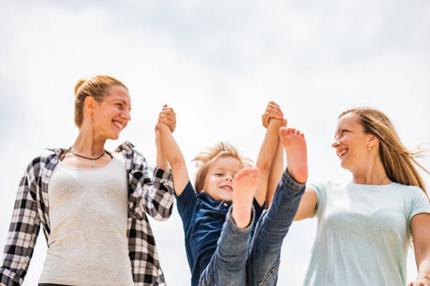 istock Two young women holding little boy for hands lifting him 1164544825