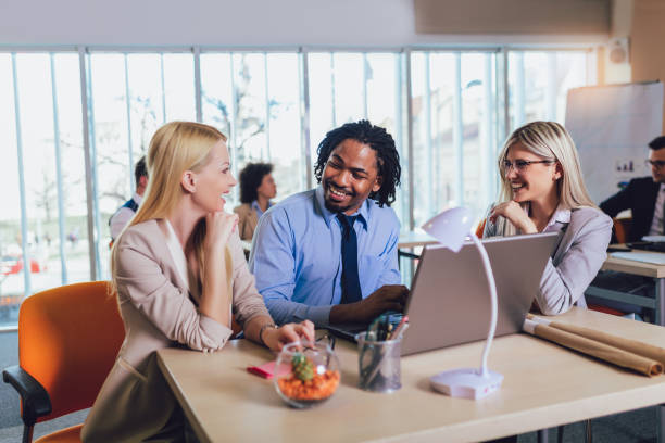 istock Group of young business people working and using laptop while sitting at the office desk together. 1164544963