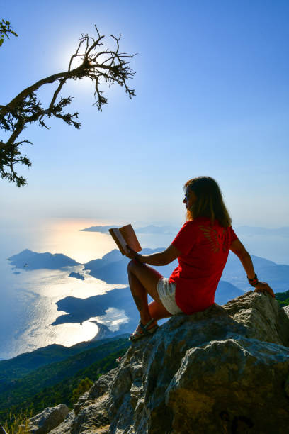 istock Woman studying book on top of mountain. 1164545036