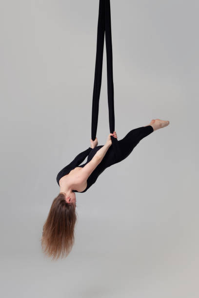 istock Beautiful girl in a black sport suit is performing an acrobatic elements in a studio 1164545156