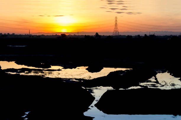istock Silhouette Electricity pole shadow in the morning low angle view on Earthen pond refraction of sunlight 1164546501