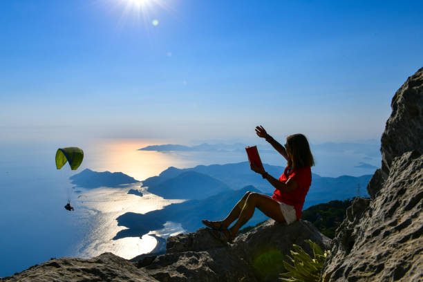 istock Woman studying book on top of mountain. 1164546717