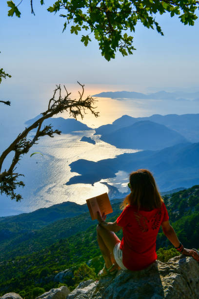 istock Woman studying book on top of mountain. 1164547543