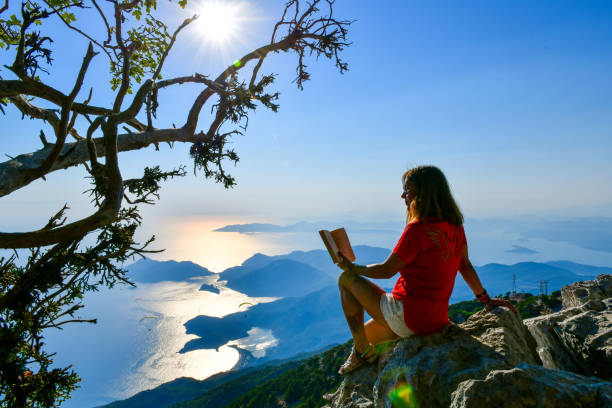 istock Woman studying book on top of mountain. 1164547845