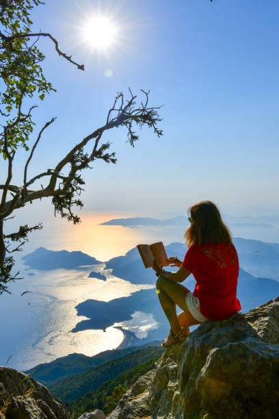 istock Woman studying book on top of mountain. 1164552134