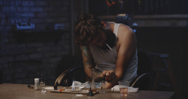 Young man overdosing drug Medium shot of a young man being writhing in pain after injecting drug drug addiction tattoos stock pictures, royalty-free photos & images