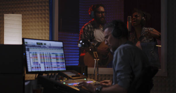 istock Vocalist guitarist and sound engineer working in studio 1164554898
