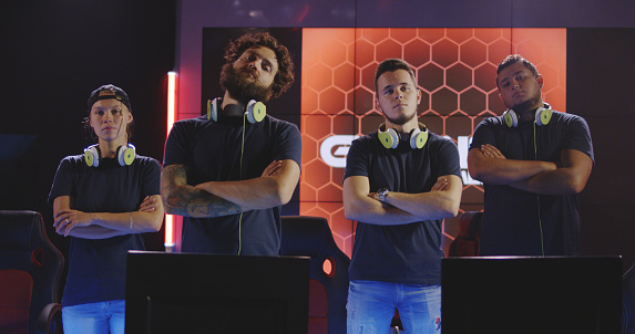 Medium shot of a confident gaming team looking at camera with arms crossed