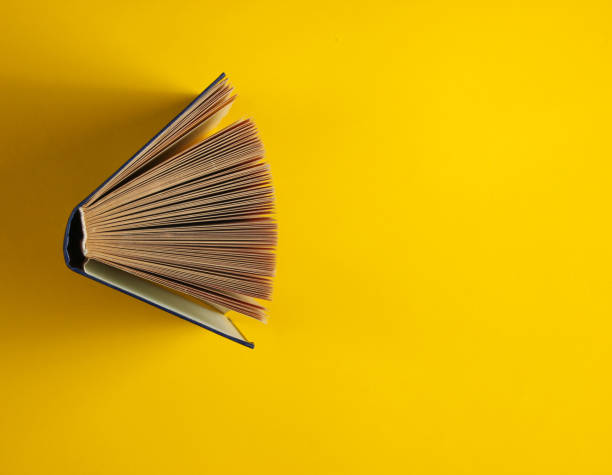 istock Open old book on a yellow background. Top view, minimalism 1164558239