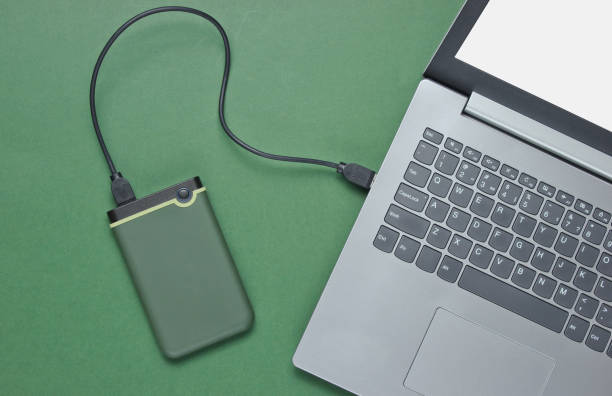 istock External hard drive connected to laptop on green background. Top view 1164558438