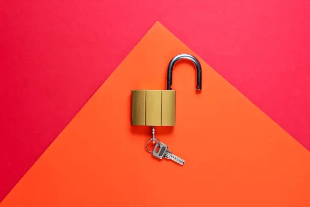 Lock and key on red-orange background. Minimalistic concept. Top view
