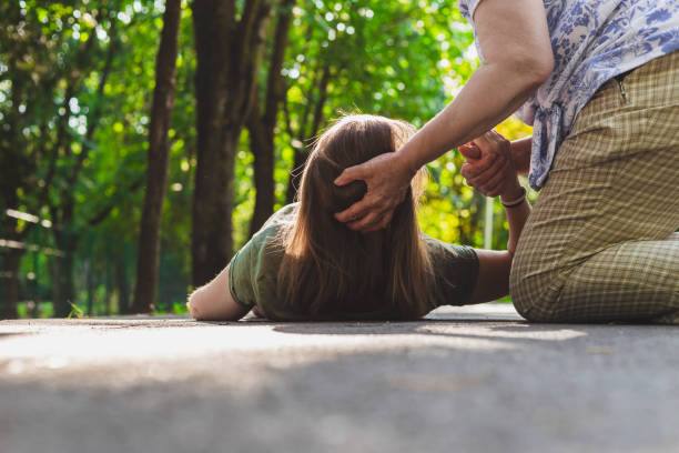 Old woman helping a fainted girl to get back on her feet stock photo