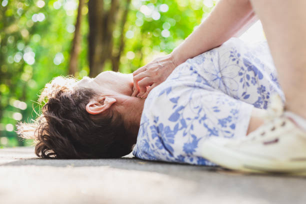 Old woman lying on the ground being checked by teenager stock photo