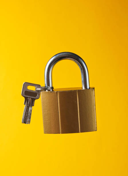 istock Metal lock with key on yellow background 1164560031