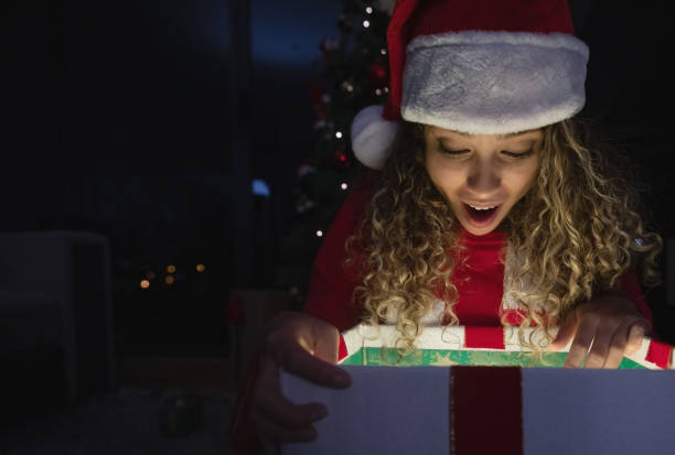 istock Surprised woman opening a Christmas present by the tree 1164561420