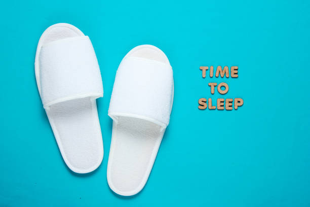 istock Time to sleep. White sleeping hotel slippers on a blue background 1164562771