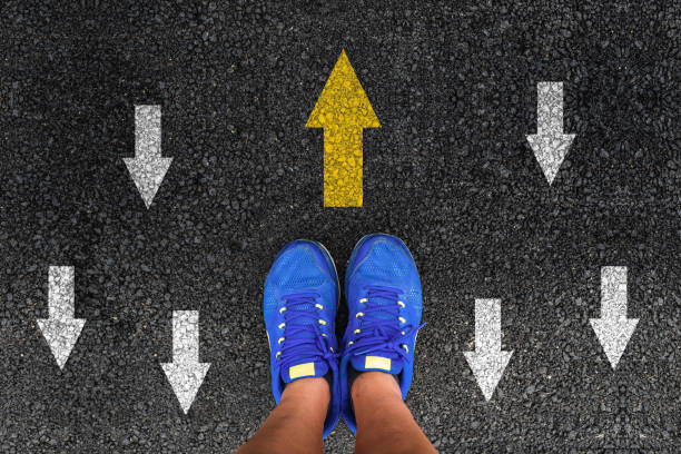istock man shoes on asphalt and opposing direction arrows on asphalt ground 1164570421