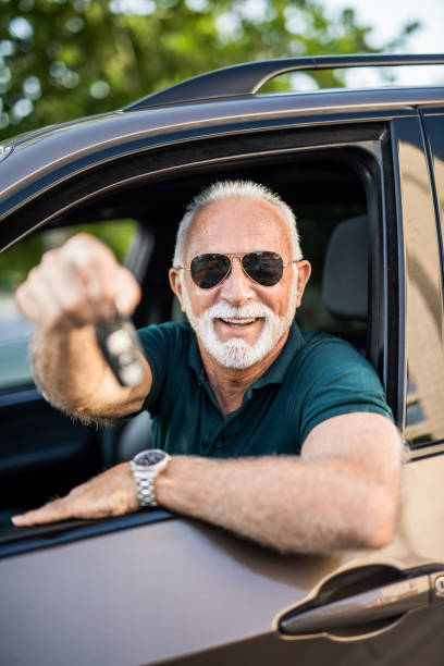 wesoły starszy mężczyzna właśnie kupił nowy samochód. - old men car vertical zdjęcia i obrazy z banku zdjęć