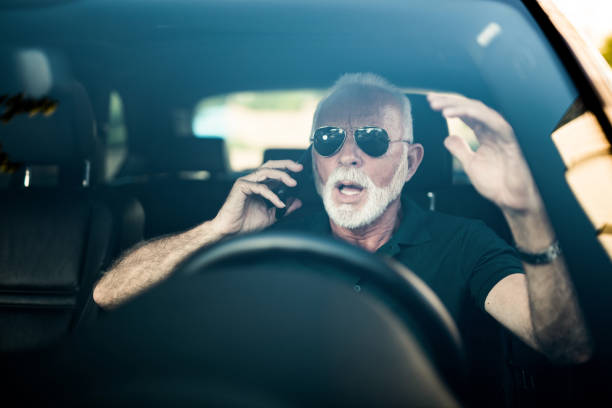 istock Senior man talking on a phone and too late to react on a car in front. 1164570827