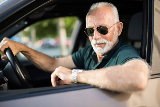 istock Senior man driving a car and checking time while in traffic. 1164572052