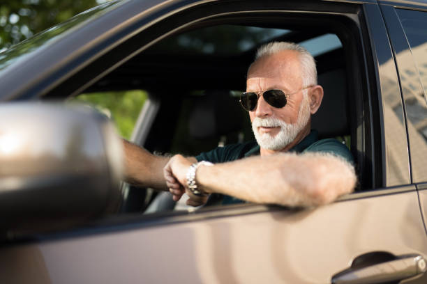 istock Senior man driving a car in traffic and checking time. 1164572059