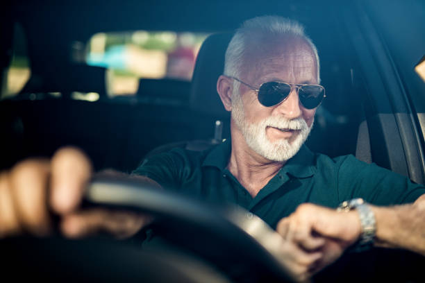 istock Senior man driving a car and checking time. 1164572069