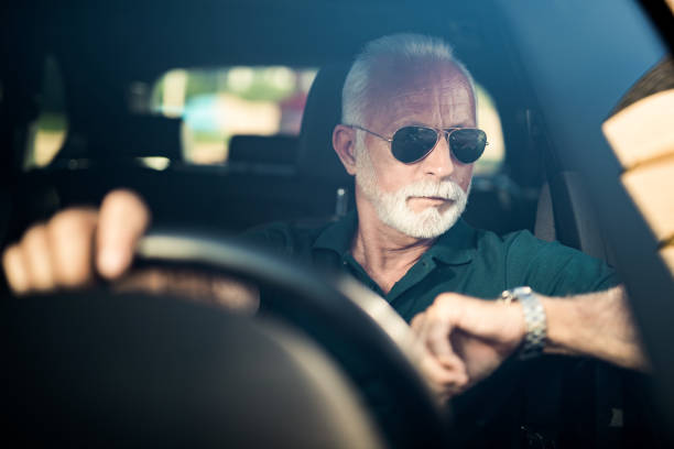 istock Senior man driving a car in traffic and checking time. 1164572086