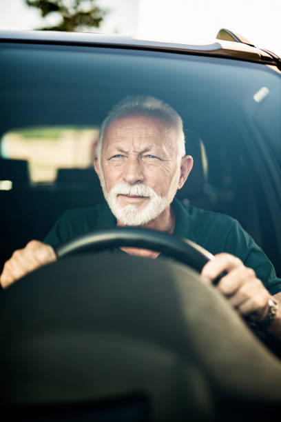 istock Senior man having eye sight problems and making effort to see while driving a car. 1164572160