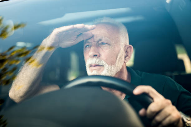 istock Senior man making effort to see the road while driving his car. 1164572180