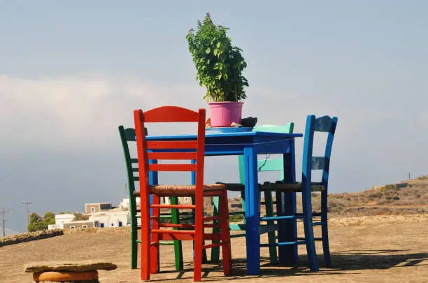 Romantic wooden vintage table with blue and red chairs in a Greek island.