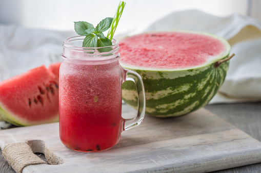 Photo of watermelon smoothie in jar with straw on light background. Fresh organic Smoothie. Health or detox diet food concept