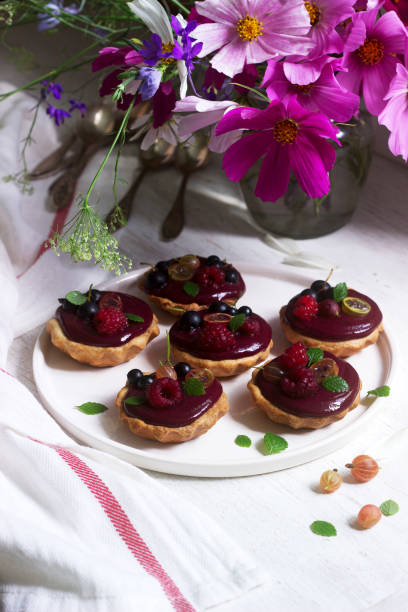 istock Shortbread tartlets with berry custard and flowers on a light background. 1164579232