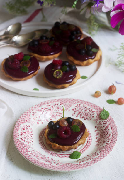 istock Shortbread tartlets with berry custard and flowers on a light background. 1164579234