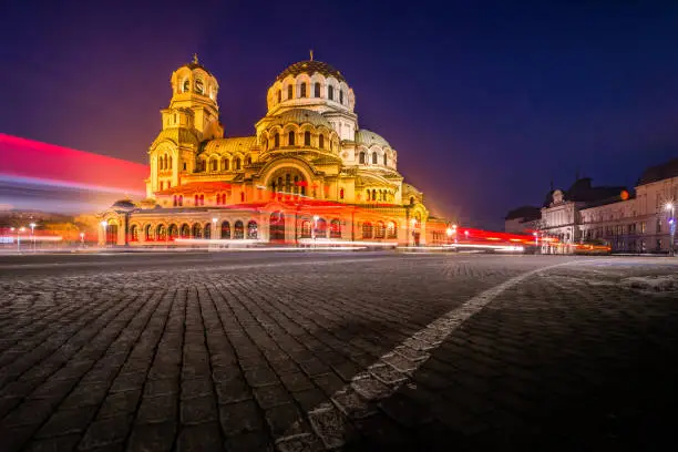 Wide angle panoramic photograph of Saint Alexander Nevsky Cathedral, downtown district in city of Sofia, capital of Bulgaria, Eastern Europe. Outdoors long exposure during night time with the evening illumination of the buildings and light trails from the passing traffic. Shot on Canon EOS R full frame system RF premium lens for best quality.