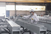 man painting metal in factory