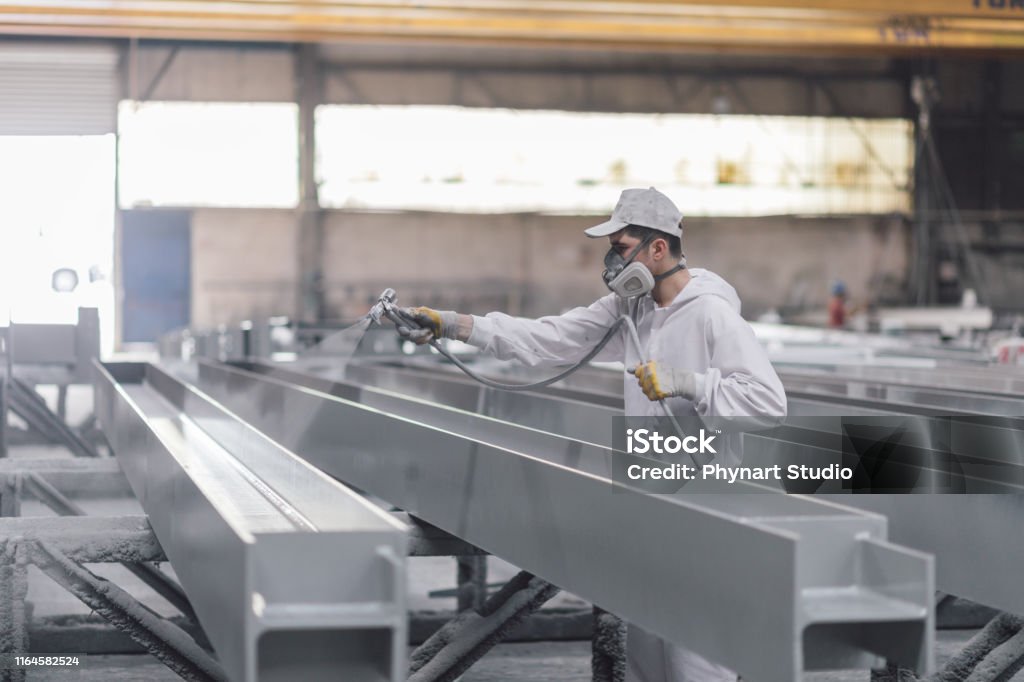 man painting metal in factory Painting - Activity Stock Photo