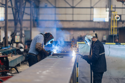 Workers are welding  part in factory