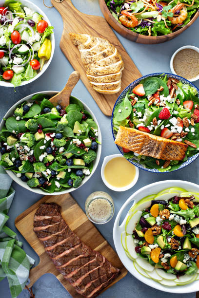 Assorted salads on the table Assorted salads with fresh ingredients on the table with grilled steak, chicken brest and salmon, clean eating concept steak salad stock pictures, royalty-free photos & images