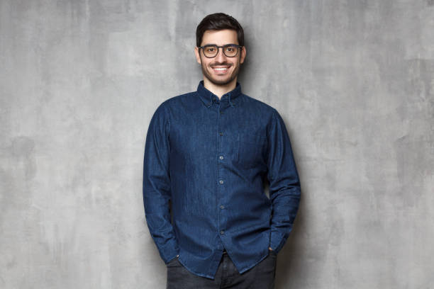istock Young handsome man wering eyeglasses, smiling and feeling confident, standing against gray textured wall background 1164586371
