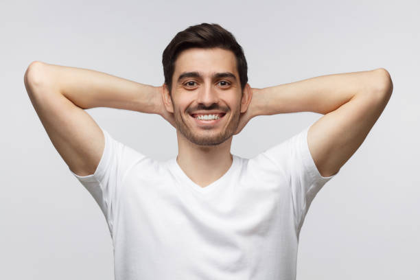 istock Young man standing isolated on gray background with arms behind head, relaxing peacefully in free time 1164586424
