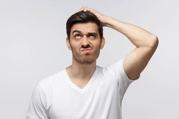 istock Young man thinking, scratching his head trying to find solution, isolated on gray background 1164586429