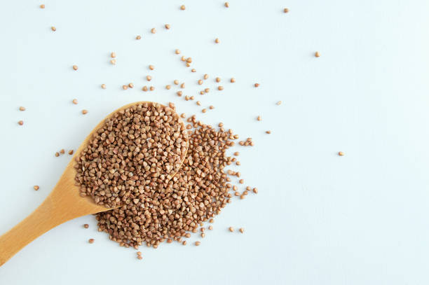 istock Buckwheat groats on a wooden spoon and scattering. White background. 1164587381