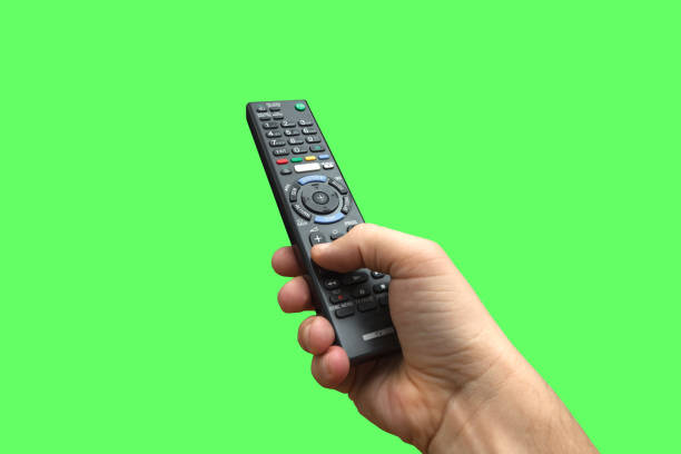 remote control in hand on isolated green screen background, path included - controlo remoto imagens e fotografias de stock