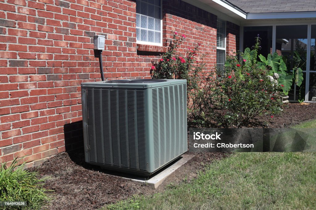 Home HVAC Unit next to modern brick home. Air Conditioner system next to a home, modern clean with bushes and brick wall Air Conditioner Stock Photo