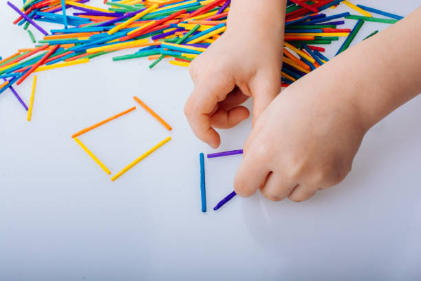 istock Kid making geometric shapes with colorful sticks on white background 1164598235