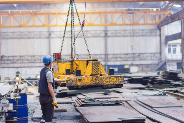 istock Overhead crane with magnetic grippers lifting steel sheets 1164598526