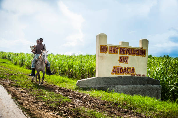Two boys on horseback ride along highway near the historic town of Trinidad, Cuba stock photo