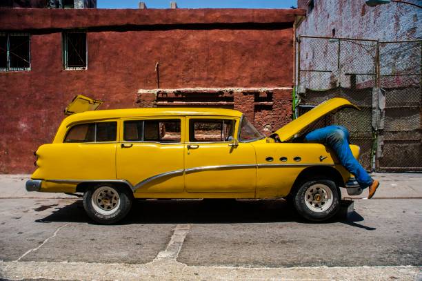 Man working under the hood of a classic car in Havana, Cuba stock photo