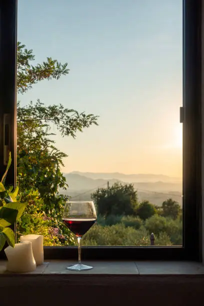 Photo of a glass of red wine stands in a window in Tuscany