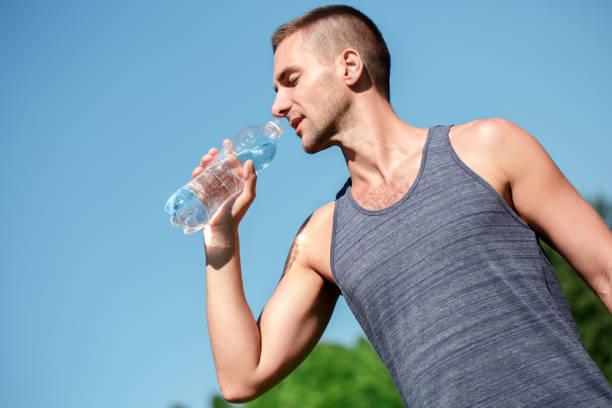 istock Healthy Lifestyle. Man practicing yoga outdoors standing with bottle dinking water thirsty bottom view 1164612211